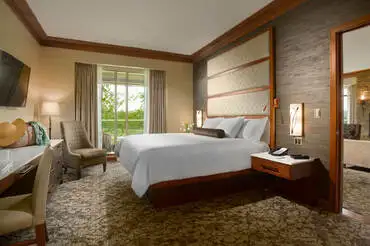 An expansive and bright living room in the VIP Suite at The Lodge at Turning Stone with a roaring fireplace and big windows overlooking central new york